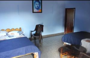 een slaapkamer met 2 bedden en een stoel. bij Malgudi Homestay in Someshwar