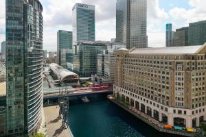 a train on a bridge over a river in a city at London Marriott Hotel Canary Wharf in London