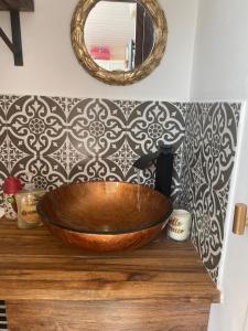 a bathroom with a wooden bowl on a counter with a mirror at Studio with a hot tub and garden in East Barnet