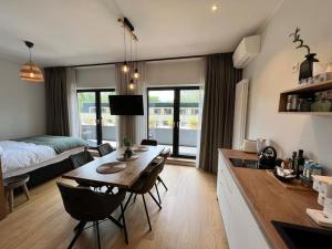 een keuken en een woonkamer met een tafel en een bed bij Nice apartment with a balcony by the sea. in Ķesterciems