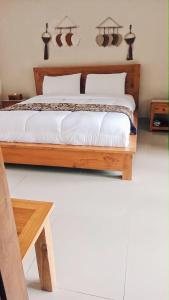 sypialnia z drewnianym łóżkiem z białą pościelą w obiekcie La Cascata Bali Munduk w mieście Munduk
