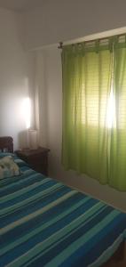 - une chambre avec un lit et un rideau vert dans l'établissement Santa Teresita frente al Mar, à Santa Teresita