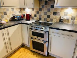 a kitchen with white cabinets and a stainless steel oven at Cosy ground floor apartment in Huntingdon +16 photos