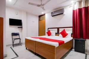 sypialnia z łóżkiem z czerwonymi poduszkami i telewizorem w obiekcie Flagship Shyam Villa w Nowym Delhi