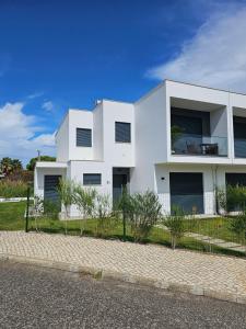 a white house with a fence in front of it at Beach House by the Lagoon - Piscina Privada in Casal do Narcizo