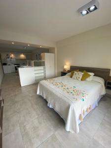 a bedroom with a large white bed and a kitchen at Apart Moderno a Estrenar Barrio Sur in San Miguel de Tucumán