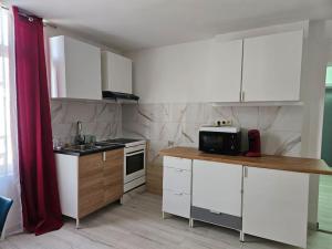 - une cuisine avec des placards blancs et un rideau rouge dans l'établissement Grand Appartement cosy et lumineux, à Mons
