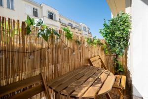 a wooden table and chairs on a patio with a fence at Renovated Studio walking distance to Paris in Montrouge