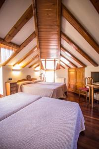 two beds in a large room with wooden ceilings at Hotel Aragüells in Benasque