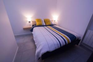 a bed with two yellow pillows in a room at L'Echo des Vagues in Le Havre