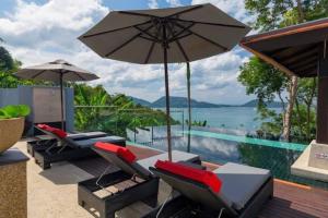 a patio with chairs and an umbrella and a pool at Patong Seaview Villa芭东一线海景豪华6卧别墅 3晚免费接机 女佣管家服务 早餐 in Patong Beach