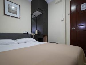 a bedroom with a white bed and a brown door at Amrise Hotel, Check in at 10PM, Check out at 9AM in Singapore