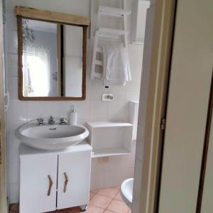 uma casa de banho branca com um lavatório e um espelho em Appartamento Giglio em Stropino