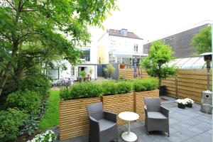 een patio met stoelen en een tafel in de tuin bij Appartementen aan den Hogeweg in Zandvoort