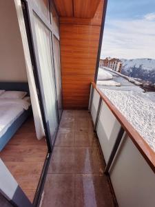 a room with a balcony with a bed and a window at Gudauri Ski Resort - Alpic Mountain View Apartments in Gudauri