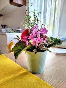 a yellow vase filled with pink flowers on a table at Apartment Sonnenschein in Dornbirn