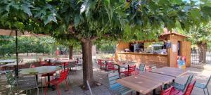 restauracja na świeżym powietrzu ze stołami i krzesłami pod drzewem w obiekcie Lodges & Nature - 71 w Awinionie