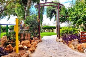 a stone walkway in a garden with a wooden arch at Bonito apartamento con vistas al mar in Playa Pobla de Farnals