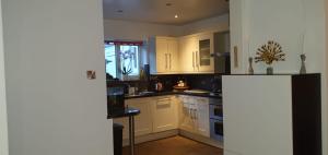 La cuisine est équipée de placards blancs et d'un réfrigérateur noir. dans l'établissement 2-Bed House in Poole, à Parkstone
