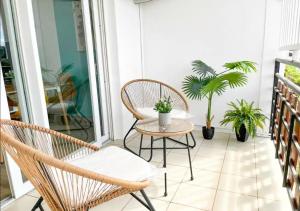 um alpendre com duas cadeiras, uma mesa e plantas em 42m2 neuf centre ville avec parking, balcon et sans coupure d'eau em Mamoudzou