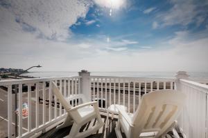 two white chairs sitting on a balcony overlooking the ocean at The Atlantic Motel in Hampton