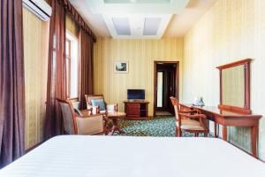 Cette chambre comprend un lit, un bureau et des chaises. dans l'établissement Western Suites Hotel, à Tachkent
