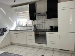 a kitchen with white cabinets and a stove top oven at Ferienwohnung Mara in Ettringen