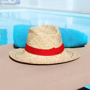 a straw hat sitting on a table next to a swimming pool at Apartamentos Calma in Playa del Ingles