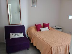 Departamento 2 Complejo Sol de Oeste في سان خوان: غرفة نوم بسرير وكرسي عليها لافته +5 صور