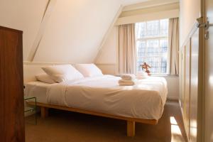 een slaapkamer met een bed met witte lakens en een raam bij hotel calisto in Amsterdam