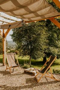 two chairs and an umbrella and a table and a tree at Prawie na końcu drogi in Rabka-Zdroj