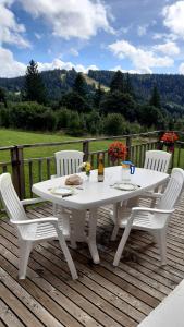 une table et des chaises blanches sur une terrasse en bois dans l'établissement Les Angéliques, à Gérardmer