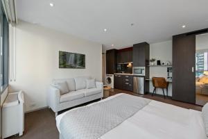 a bedroom with a bed and a couch and a kitchen at City Stays in Melbourne