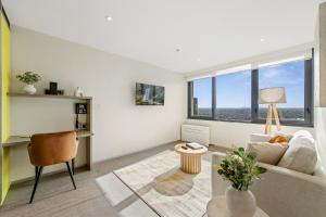 a living room with a couch and a desk and windows at City Stays in Melbourne