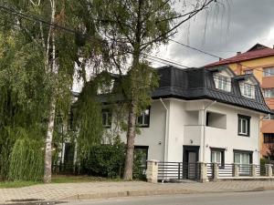 uma casa branca com um telhado preto em B59 BOUTIQUE HOTEL em Câmpulung Moldovenesc