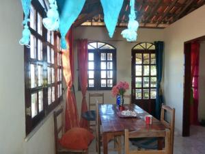 una sala da pranzo con tavolo, sedie e finestre di VILLA com Wi-Fi, cozinha, parking, Canoa Quebrada zona centro, jardim tropical, tudu prossimo a pe a Canoa Quebrada