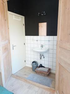 La salle de bains est pourvue d'un lavabo et d'un mur carrelé blanc. dans l'établissement B&B Emma, à Bruges