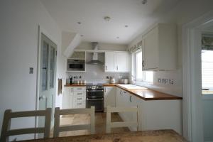 una cucina con mobili bianchi, tavolo e sedie di Gortnagory Cottage Carnlough a Carnlough