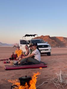 a group of people sitting around a fire in the desert at Wadi Rum Star Camp in Wadi Rum