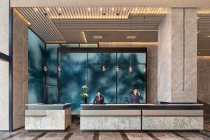 a lobby of a hotel with two people in the mirror at Courtyard by Marriott Hangzhou West in Hangzhou