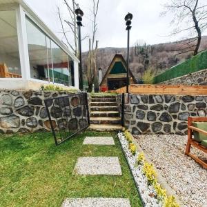 a garden with a stone wall and a house at Sapanca Sudere Bungalov 2 in Sakarya