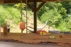 - une table en bois avec une boisson et un bol de fruits dans l'établissement Le Loys Martinique, à Sainte-Anne