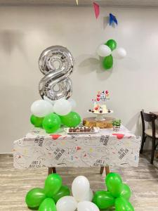 una mesa con globos verdes y blancos y un número ocho en Pousada Paraíso Tropical, en Penha