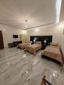 2 łóżka w dużym pokoju z marmurową podłogą w obiekcie iHome Petra w mieście Wadi Musa