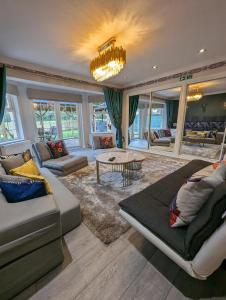 uma sala de estar com um sofá e uma mesa em FINN VILLAGE "Raspberry Cottage" Private Garden, 6-seater Hot Tub, Firepit & Pizza Stove em Glasgow