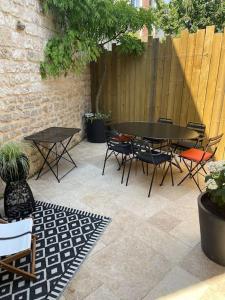 een patio met een tafel en stoelen en een hek bij Maison en centre ville avec extérieur in Compiègne