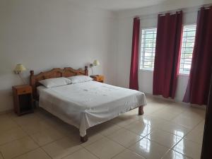 a bedroom with a large bed with red curtains at Palmont Commercial Self-Catering Apartments - Beau Vallon in Beau Vallon