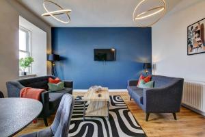 sala de estar con 2 sillas y pared azul en The Irvine - Coorie Doon Apartments, en Irvine
