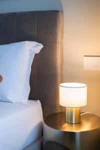 una lámpara en una mesa junto a una cama en Heart Milan Apartments Sforza Duomo, en Milán