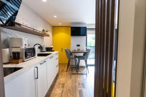 a kitchen with white cabinets and a yellow accent wall at Apartments DREAM in Málaga